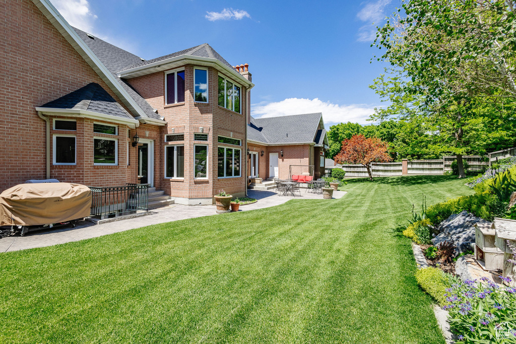 Back of property with a patio area, a fenced backyard, a chimney, brick siding, and entry steps