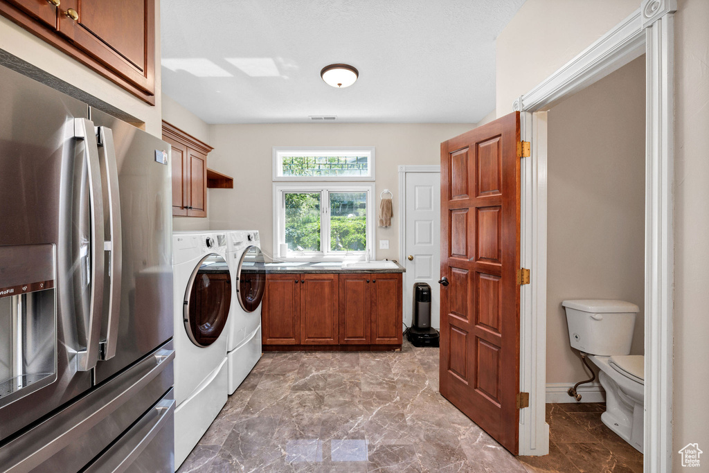 Washroom featuring washer and clothes dryer, marble finish flooring, and cabinet space