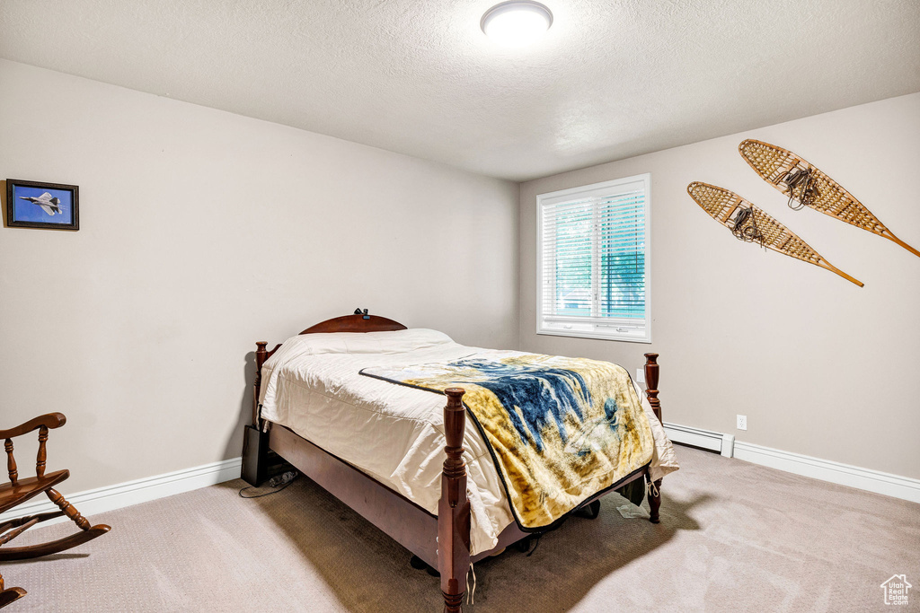 Carpeted bedroom with a baseboard radiator and a textured ceiling