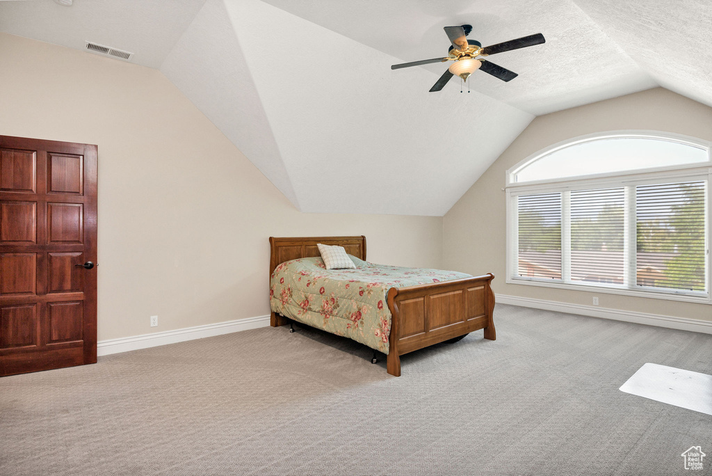 Bedroom featuring light colored carpet, lofted ceiling, and ceiling fan