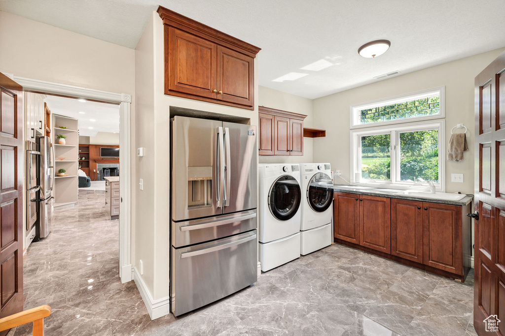 Washroom with washing machine and clothes dryer, light marble finish floors, and cabinet space