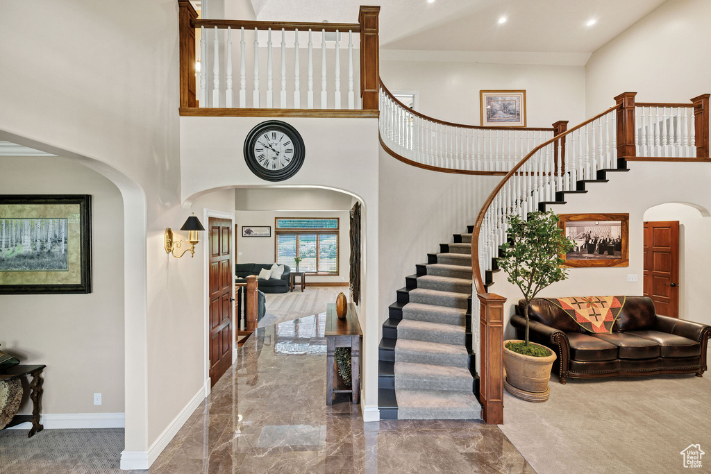 Entrance foyer featuring arched walkways, a towering ceiling, stairway, marble tiled floors, and recessed lighting