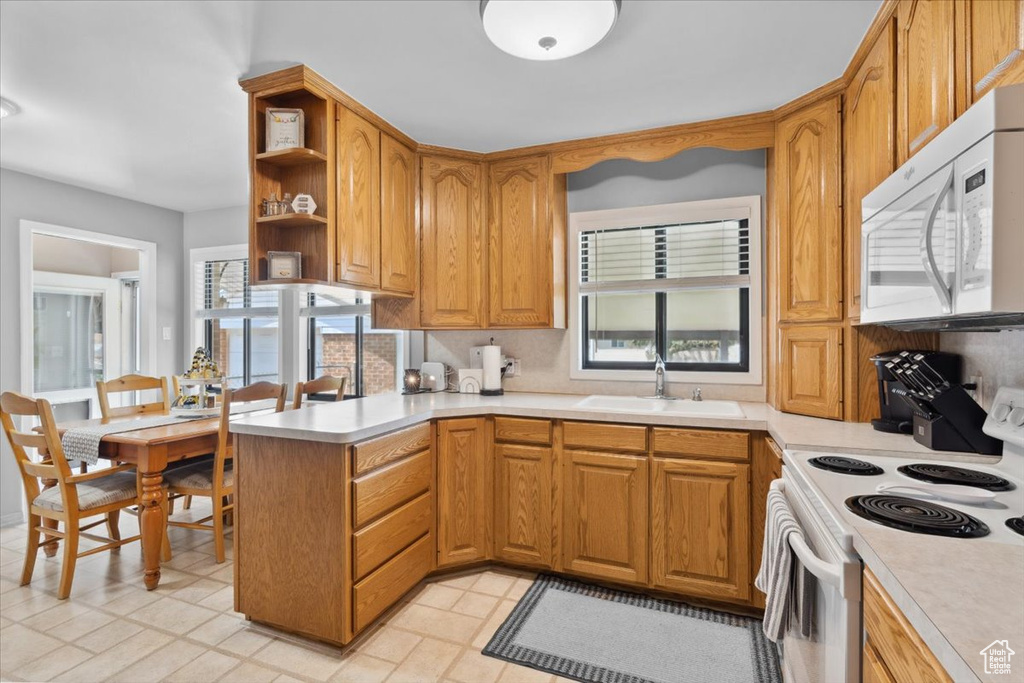 Kitchen featuring white appliances, a peninsula, light countertops, and open shelves