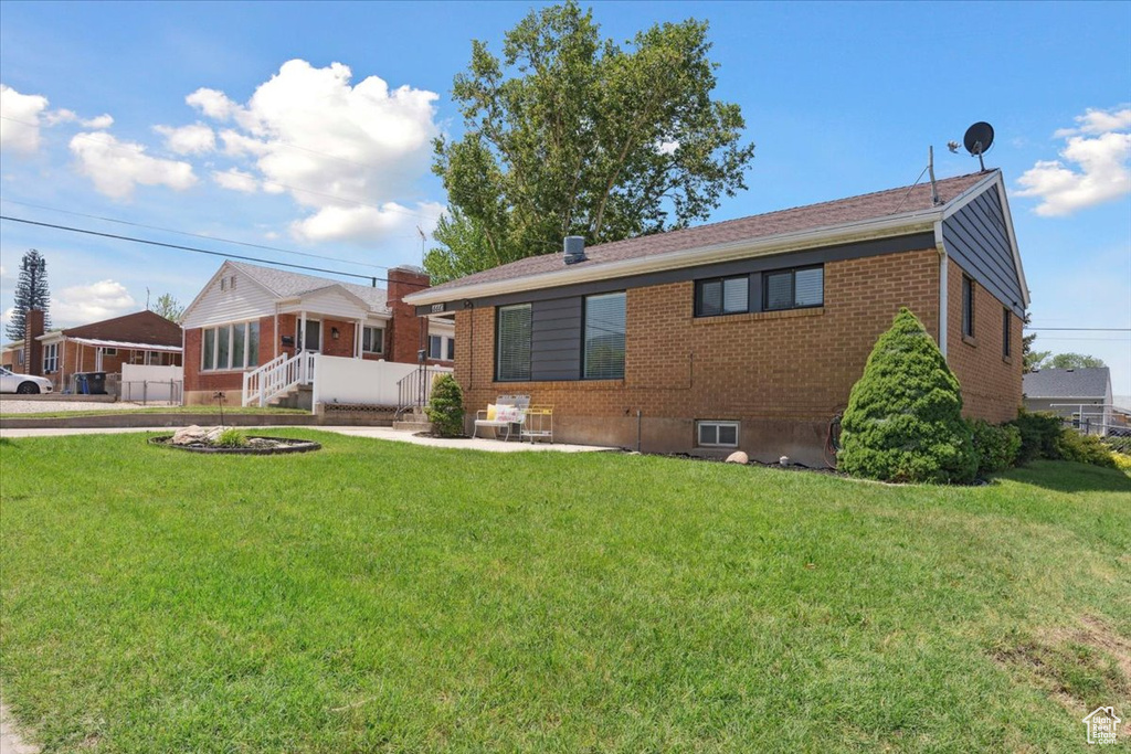 View of front of property with brick siding, a front yard, and a patio