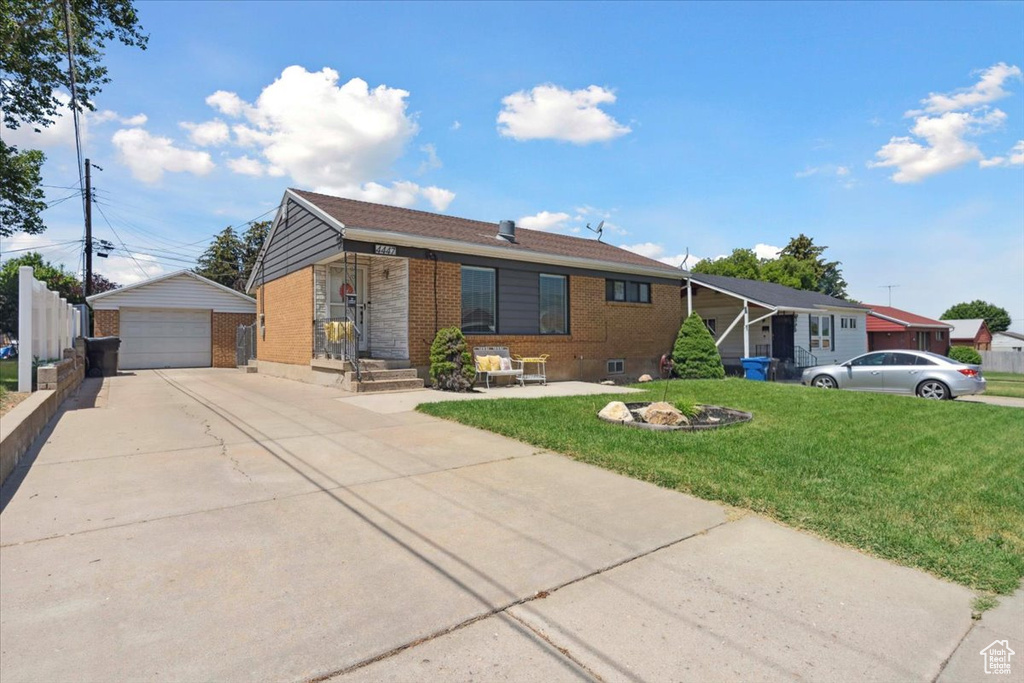 Ranch-style house with brick siding, an outbuilding, a detached garage, and a front lawn