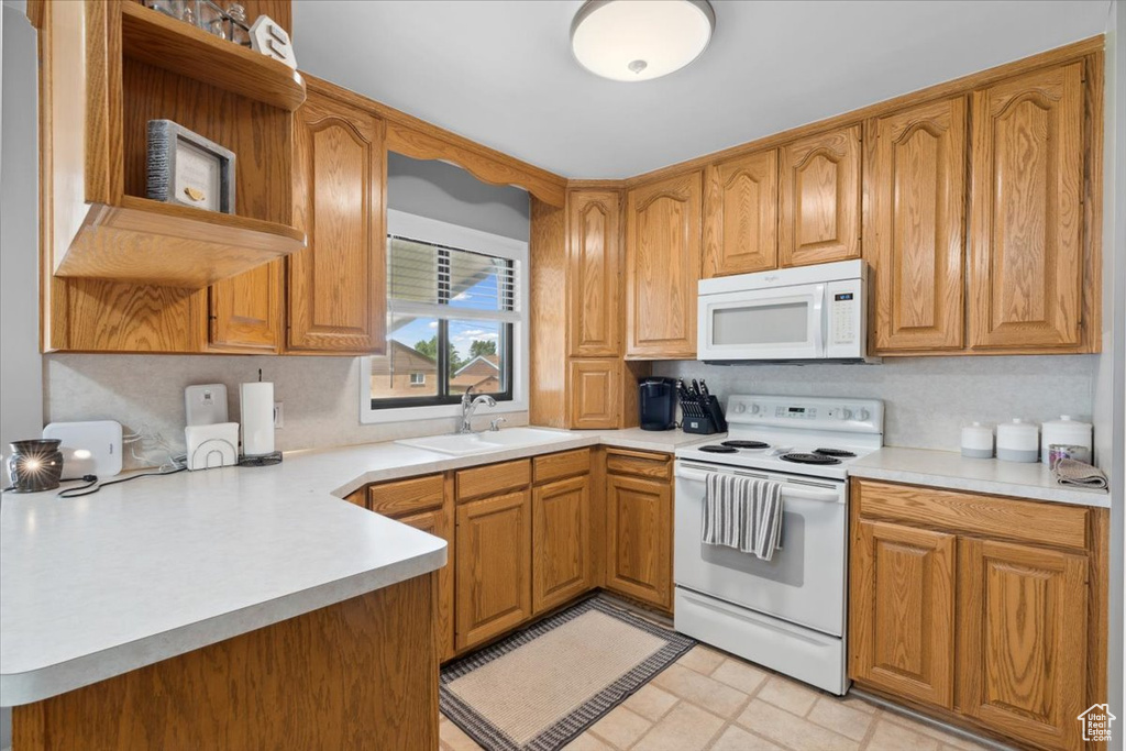 Kitchen featuring white appliances, open shelves, light countertops, a peninsula, and backsplash