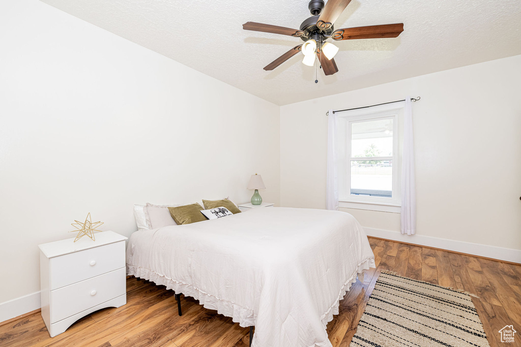 Bedroom with wood finished floors, ceiling fan, and a textured ceiling