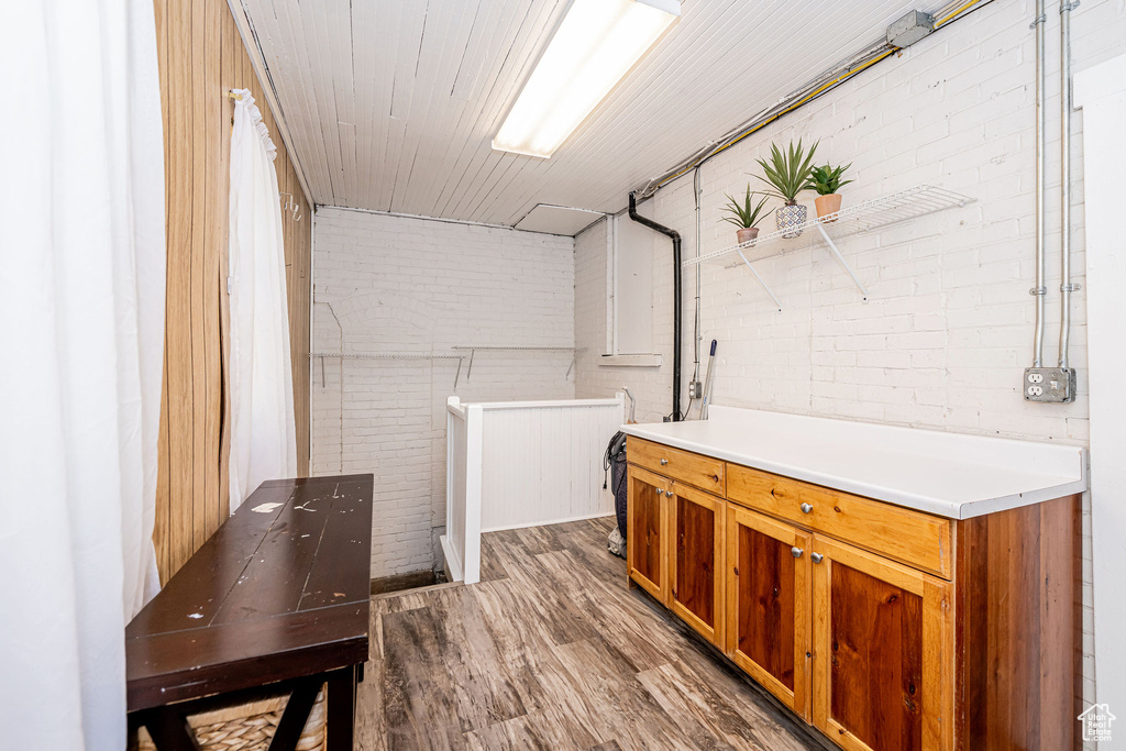 Washroom with wood finished floors and brick wall