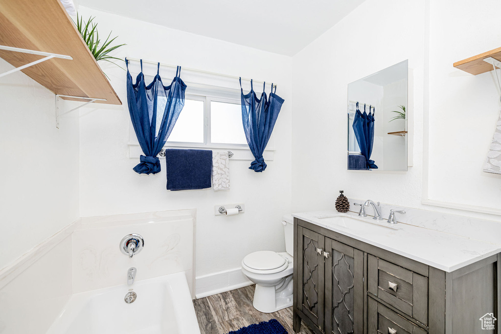 Bathroom featuring a garden tub, vanity, and wood finished floors