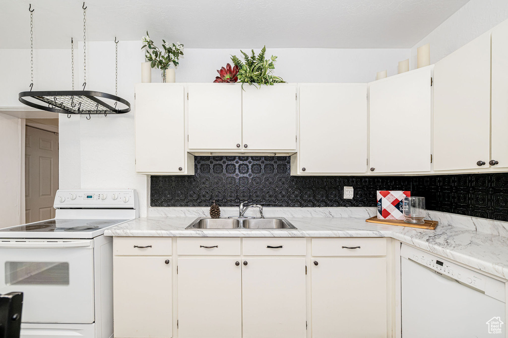 Kitchen with white appliances, light countertops, and backsplash