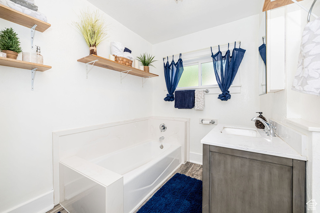 Bathroom with a bath, vanity, and wood finished floors