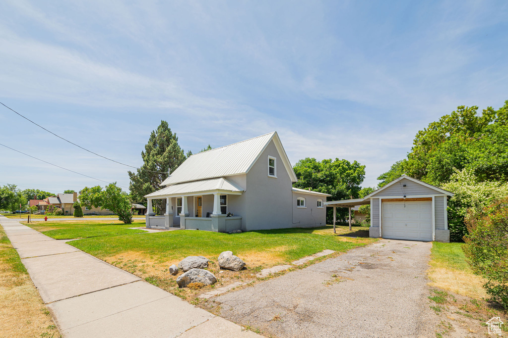 View of front of house with a front lawn, a garage, an outbuilding, and driveway