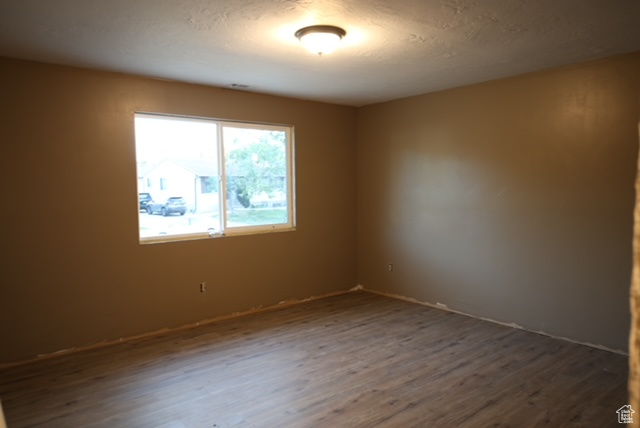 Empty room featuring dark wood-style floors and a textured ceiling