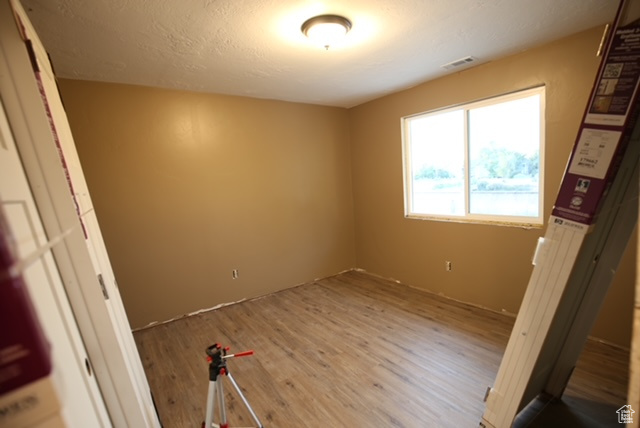 Spare room with wood finished floors and a textured ceiling