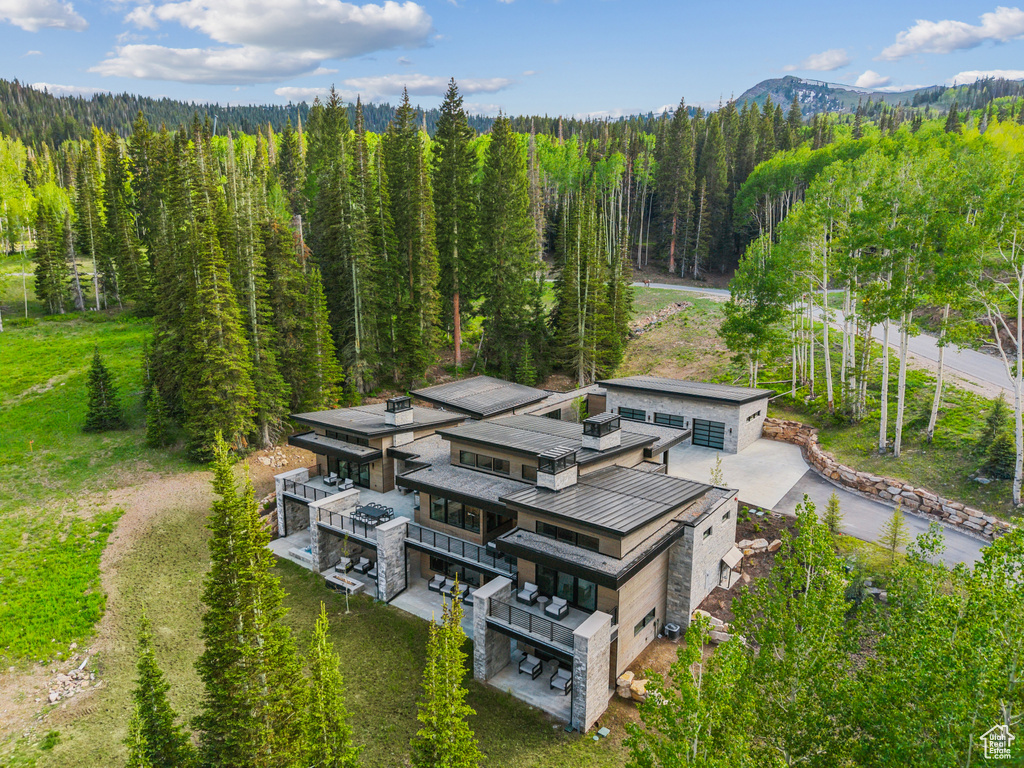 Aerial view of property and surrounding area featuring a heavily wooded area and mountains