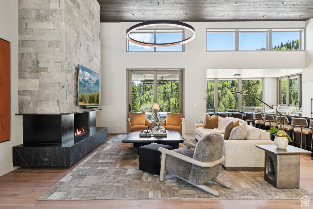 Living area featuring wood finished floors, a lit fireplace, a high ceiling, and wooden ceiling