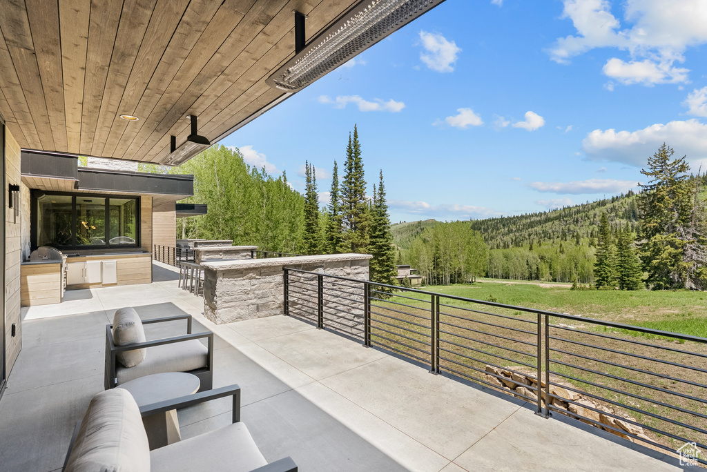 View of patio featuring area for grilling, a forest view, and an outdoor bar