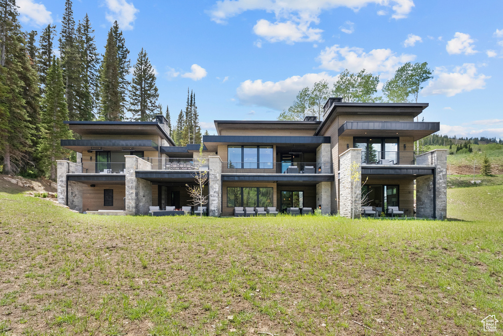 Rear view of property with a balcony and a yard
