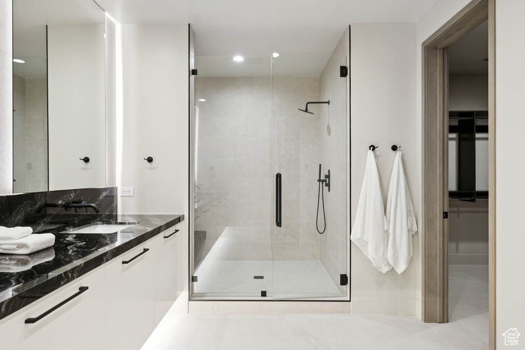 Full bath featuring vanity, a shower stall, recessed lighting, a walk in closet, and tile patterned flooring