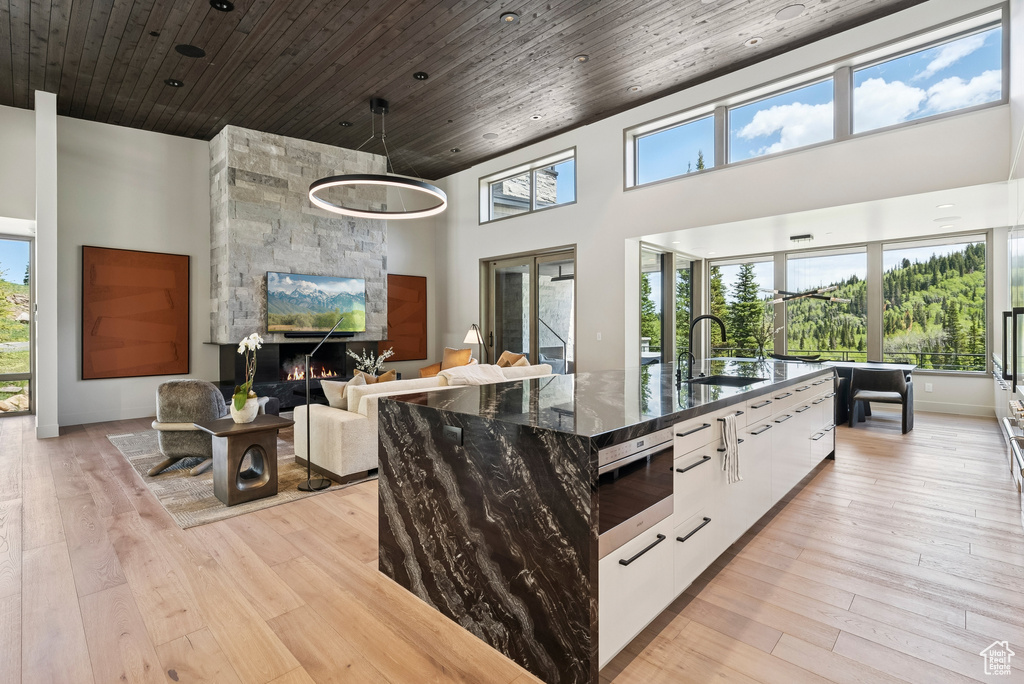 Kitchen with stainless steel microwave, modern cabinets, a kitchen island with sink, white cabinets, and dark stone countertops