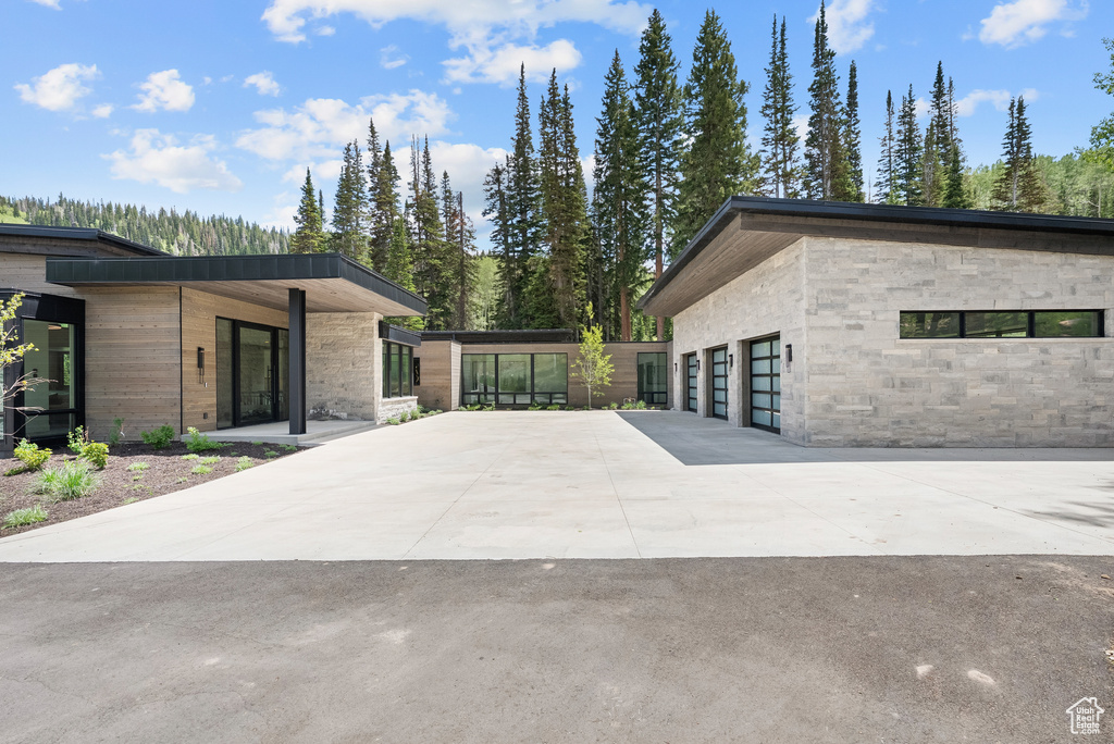 View of side of home with driveway, stone siding, and an attached garage