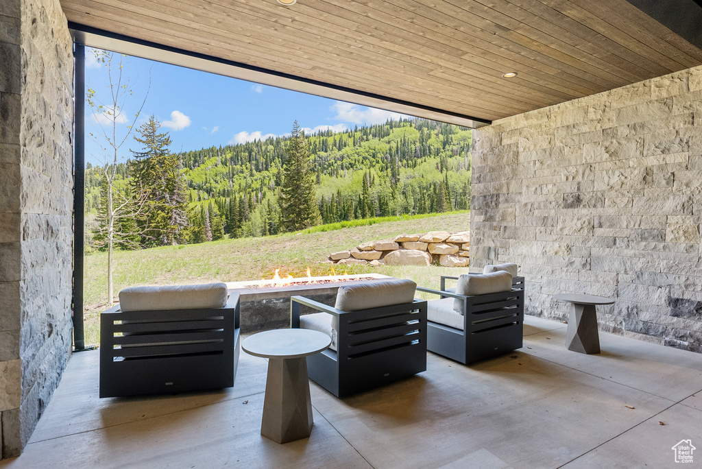 View of patio featuring a wooded view and a fire pit