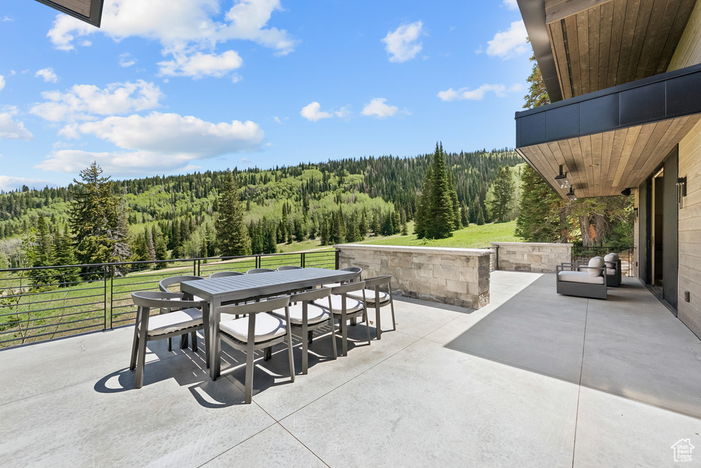 View of patio with a forest view and outdoor dining area