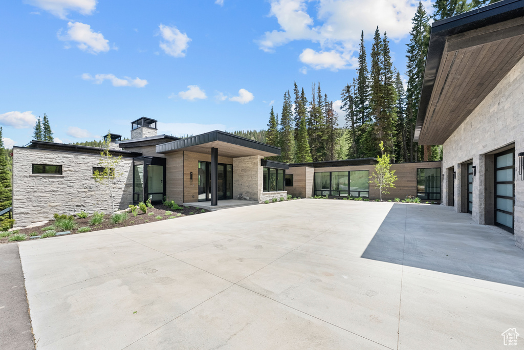 View of front of home with stone siding, a chimney, and concrete driveway