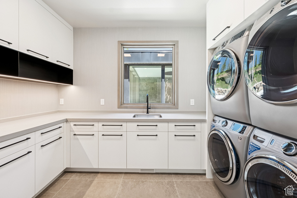 Laundry area featuring stacked washer / dryer, cabinet space, and light tile patterned floors