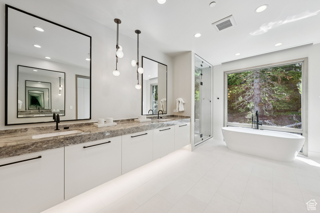 Bathroom featuring double vanity, a freestanding tub, a stall shower, recessed lighting, and tile patterned floors