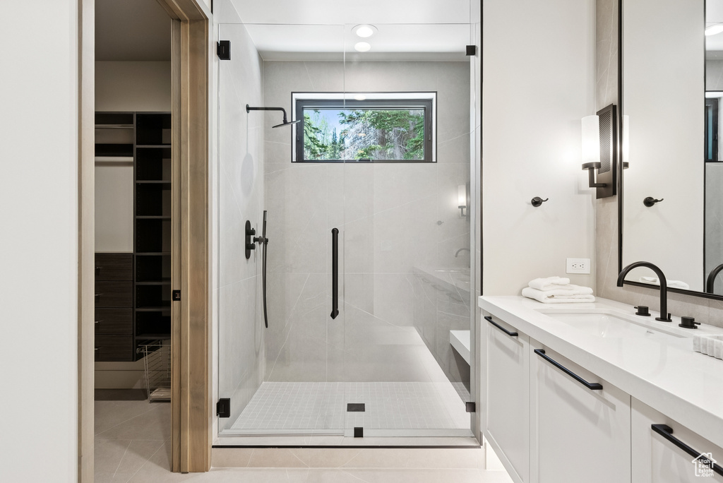Full bathroom with vanity, a stall shower, a spacious closet, and tile patterned floors