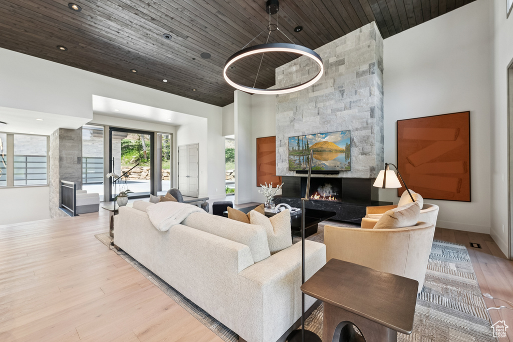Living area featuring a fireplace, wood ceiling, wood finished floors, a towering ceiling, and recessed lighting