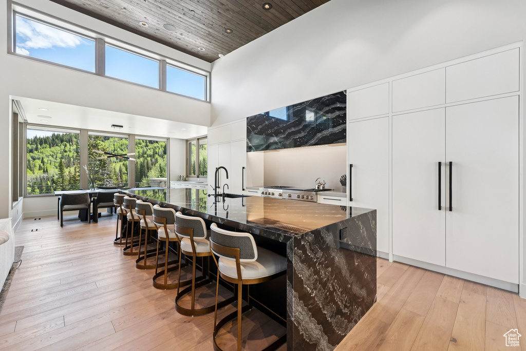 Bar featuring a high ceiling, light wood-style flooring, wood ceiling, and recessed lighting