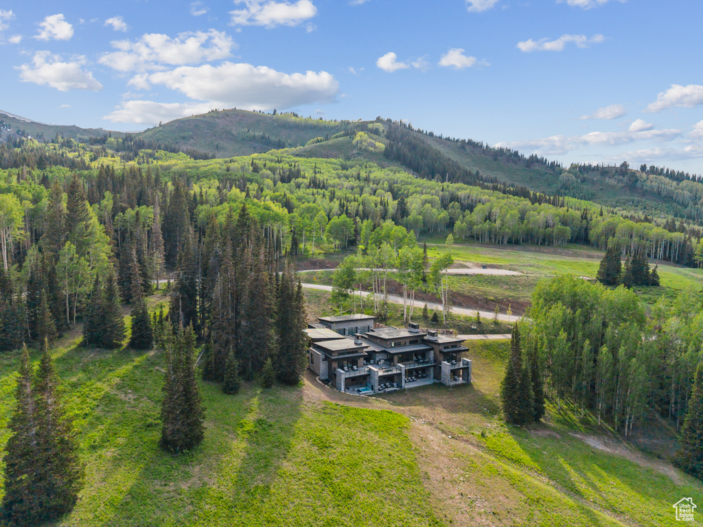 Aerial view of property and surrounding area with a forest and mountains