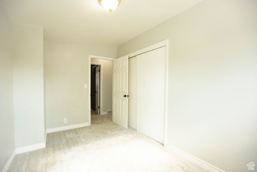 Unfurnished bedroom with light carpet and a closet