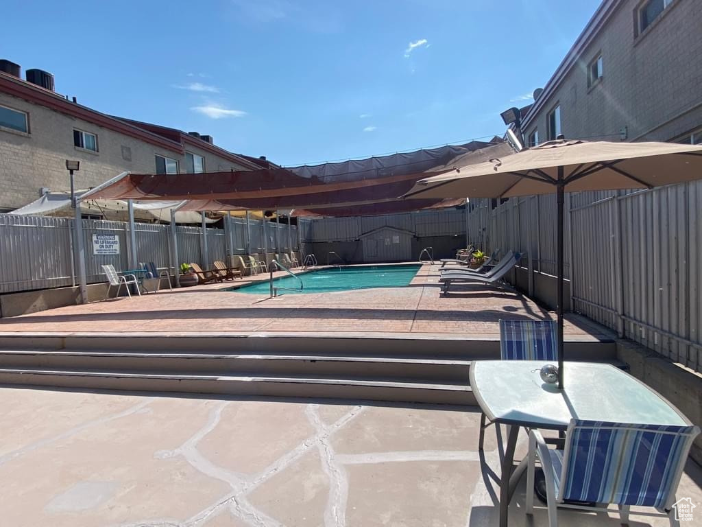 Community pool with a fenced backyard and a patio area