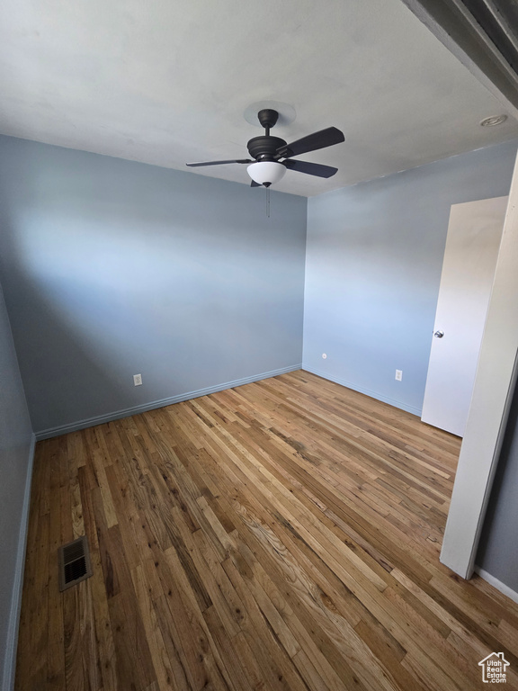 Empty room with a ceiling fan and hardwood / wood-style flooring
