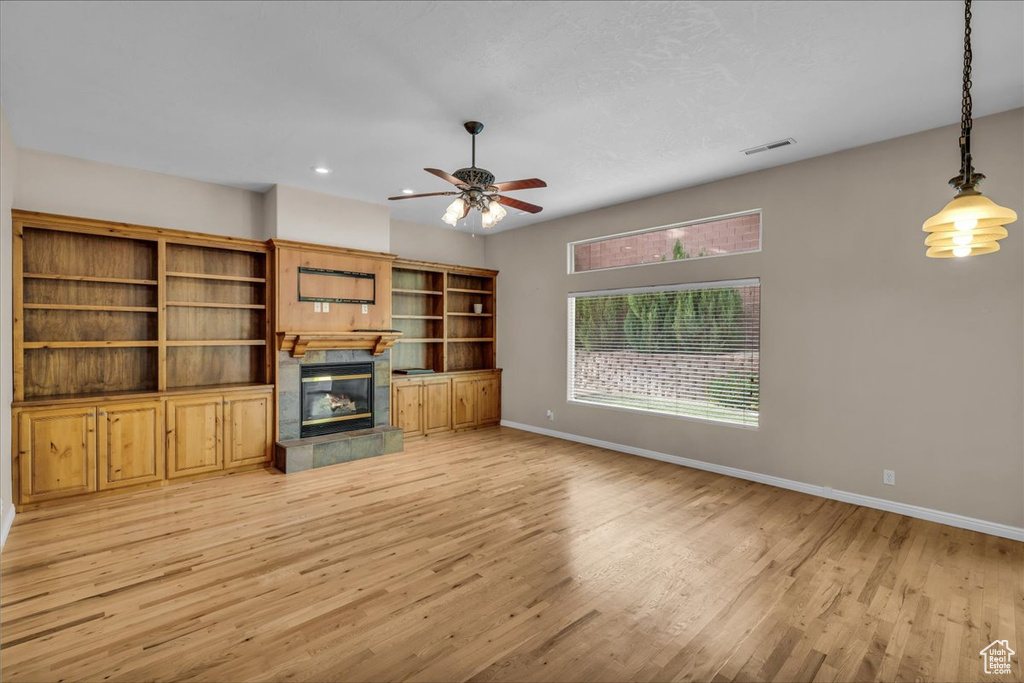 Unfurnished living room with light wood finished floors, a tiled fireplace, ceiling fan, and recessed lighting