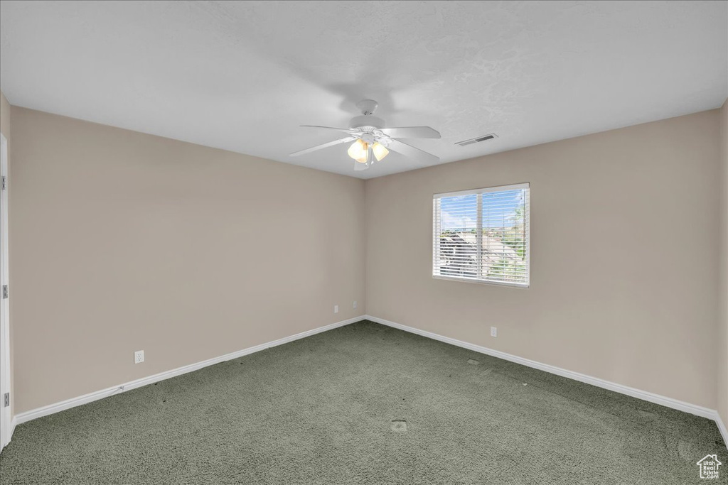 Empty room with a ceiling fan and carpet floors