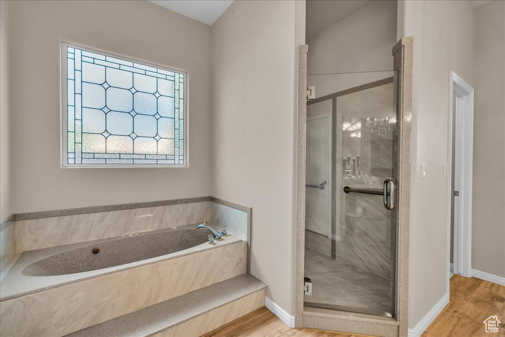 Full bathroom featuring wood finished floors, a bath, and a stall shower