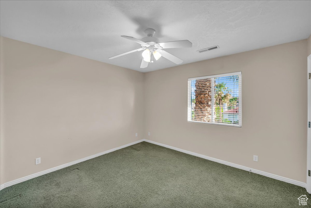 Empty room featuring dark carpet and ceiling fan