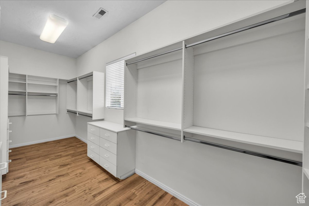 Walk in closet with light wood finished floors