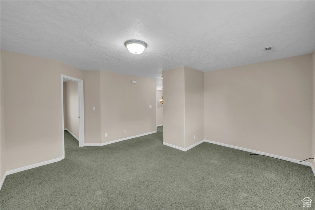 Unfurnished room with dark colored carpet and a textured ceiling
