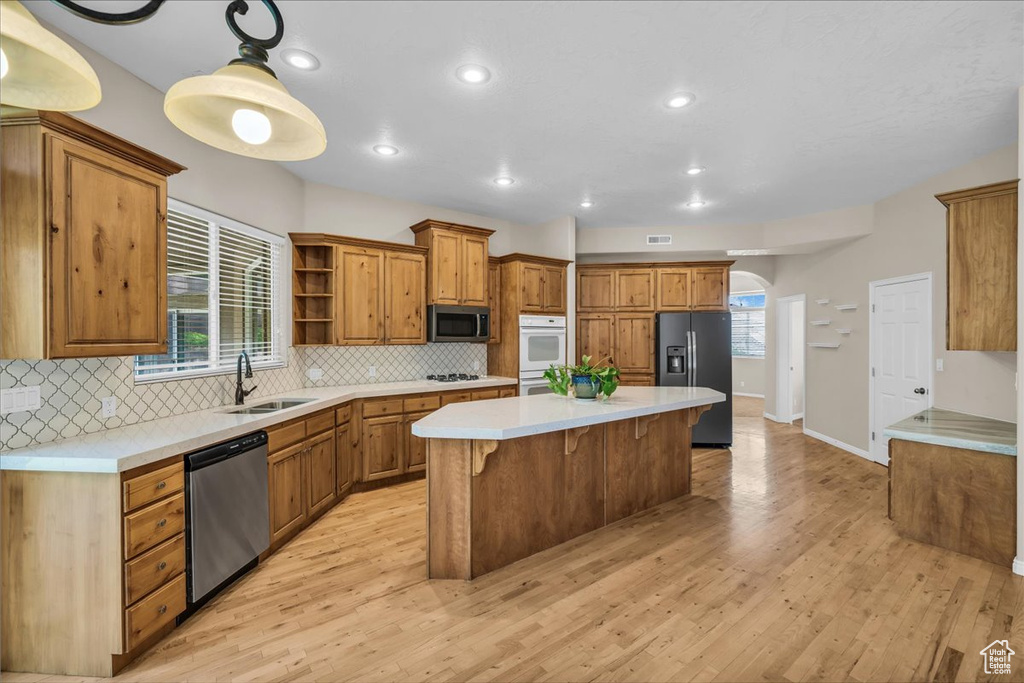 Kitchen with stainless steel appliances, open shelves, a kitchen island, decorative backsplash, and recessed lighting