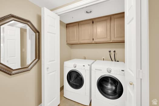 Washroom with cabinet space and washing machine and clothes dryer