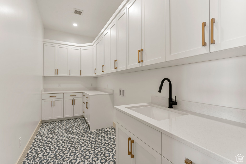 Washroom featuring cabinet space, washer hookup, baseboards, tile patterned floors, and recessed lighting