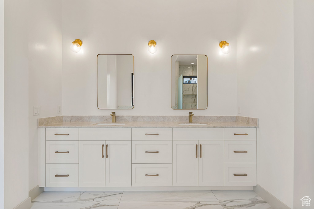 Bathroom with marble finish flooring, baseboards, and double vanity
