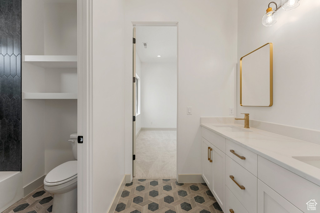 Full bath featuring double vanity, toilet, and baseboards