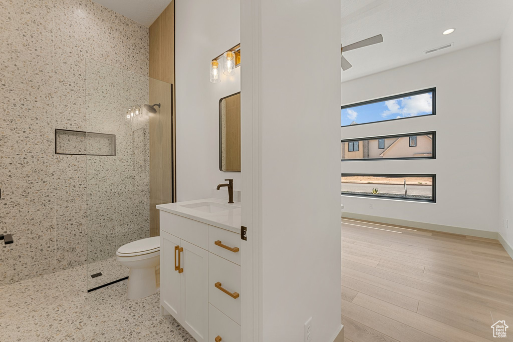 Full bath with vanity, a walk in shower, toilet, a ceiling fan, and recessed lighting