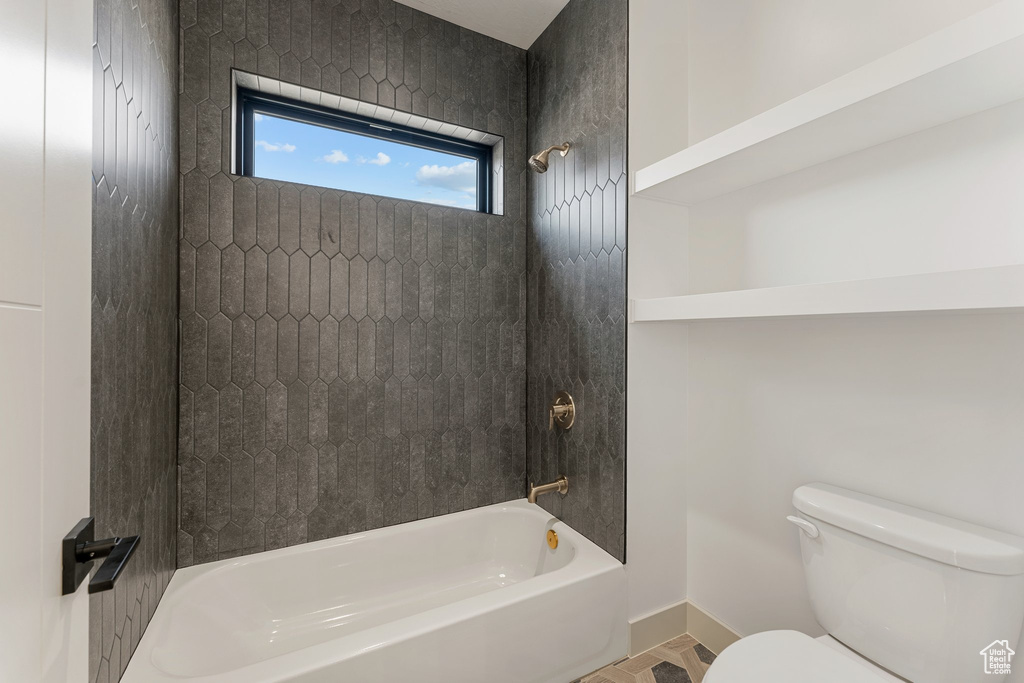 Bathroom featuring toilet,  shower combination, and baseboards